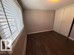 Room featuring wood-finish flooring, neutral wall paint, white baseboards, and a window with horizontal blinds - 