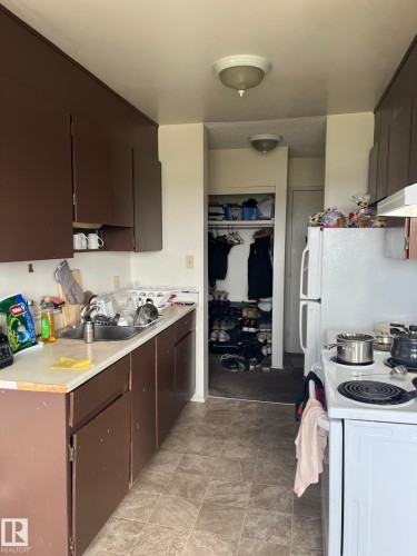 Kitchen featuring brown cabinetry, white countertops, a stainless steel sink, and tile-look flooring - 68 11265 31 Avenue, Edmonton, AB - Indoor Photo Showing Kitchen