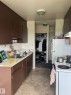 Kitchen featuring brown cabinetry, white countertops, a stainless steel sink, and tile-look flooring - 68 11265 31 Avenue, Edmonton, AB  - Indoor Photo Showing Kitchen 