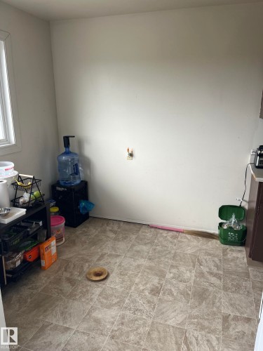 Neutral-toned square tile flooring extends throughout the space, complemented by a white wall finish and a partial window offering natural light - 68 11265 31 Avenue, Edmonton, AB - Indoor