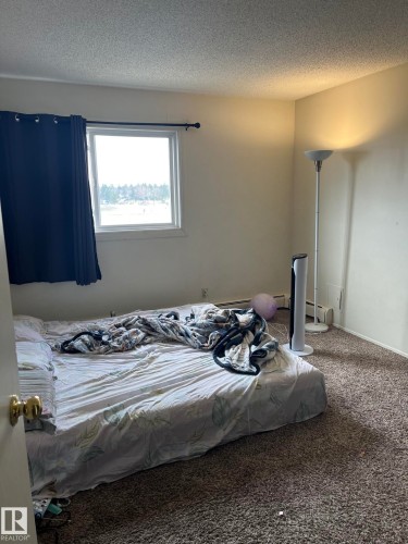 Carpeted room with a single window featuring a dark curtain and a window rod - 68 11265 31 Avenue, Edmonton, AB - Indoor Photo Showing Bedroom