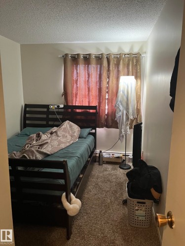 Bedroom featuring carpet flooring, a window with curtain rod and eyelet curtains, and neutral wall paint - 68 11265 31 Avenue, Edmonton, AB - Indoor