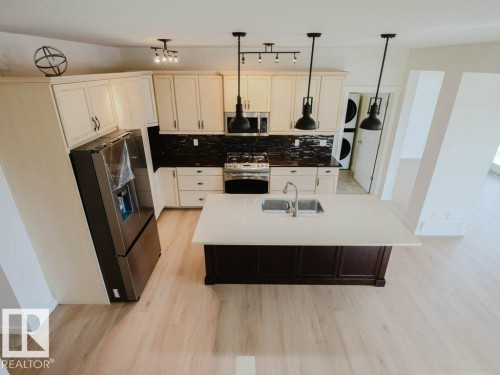Kitchen featuring light wood-finish flooring and cream-colored cabinetry - 15867 11 Avenue, Edmonton, AB - Indoor Photo Showing Kitchen With Double Sink