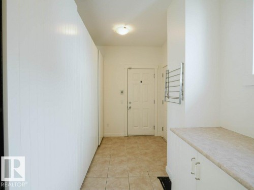 Entryway from Garage featuring ceramic tile flooring, a built-in storage unit with a countertop, and a wall-mounted drying rack - 15867 11 Avenue, Edmonton, AB - Indoor Photo Showing Other Room