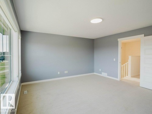 Spacious room featuring neutral carpeting and light gray walls - 15867 11 Avenue, Edmonton, AB - Indoor Photo Showing Other Room