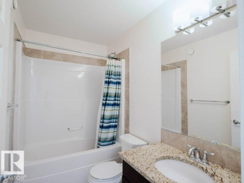 Bathroom featuring a combination bathtub and shower with neutral-toned tile surround - 15867 11 Avenue, Edmonton, AB - Indoor Photo Showing Bathroom