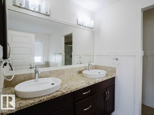 Double vanity featuring vessel sinks, polished chrome fixtures, and a granite-finish countertop - 15867 11 Avenue, Edmonton, AB - Indoor Photo Showing Bathroom