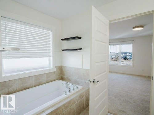 Soaking tub with tile surround and chrome fixtures - 15867 11 Avenue, Edmonton, AB - Indoor Photo Showing Bathroom