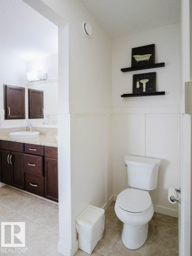 Well-appointed bathroom featuring a white toilet, wainscoting, and tile flooring - 15867 11 Avenue, Edmonton, AB - Indoor Photo Showing Bathroom