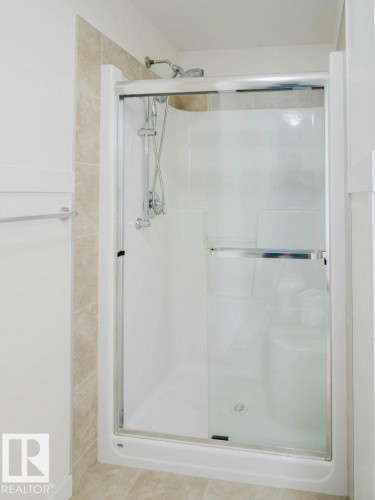 Shower enclosure with clear glass sliding doors and an integrated shower system - 15867 11 Avenue, Edmonton, AB - Indoor Photo Showing Bathroom