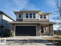 Two-story residence featuring a stone and siding exterior, an attached two-car garage, multiple upper-level windows, a covered front entry, and a concrete driveway - 15867 11 Avenue, Edmonton, AB  - Outdoor 