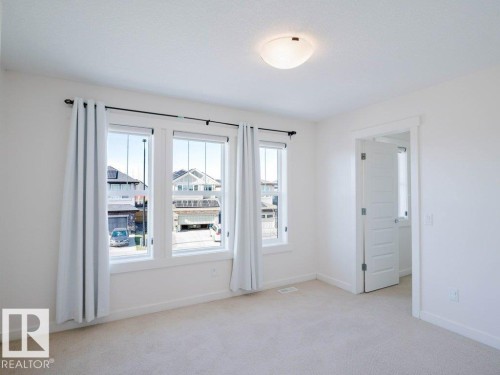 Bright interior space featuring light-toned carpeting and white walls - 15867 11 Avenue, Edmonton, AB - Indoor Photo Showing Other Room