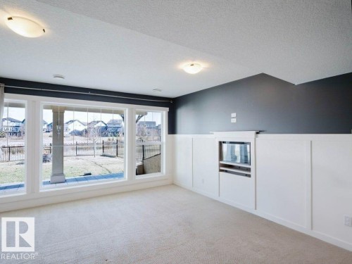 Recessed media niche within wainscoting, complemented by full-height windows and light-toned carpeting - 15867 11 Avenue, Edmonton, AB - Indoor Photo Showing Other Room