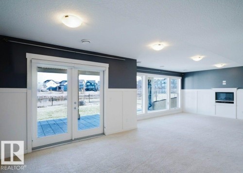 Spacious carpeted room featuring a built-in electric fireplace and wall-mounted television niche - 15867 11 Avenue, Edmonton, AB - Indoor Photo Showing Other Room