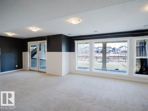 Finished lower level with neutral carpet, white wainscoting, and large windows - 15867 11 Avenue, Edmonton, AB - Indoor Photo Showing Other Room