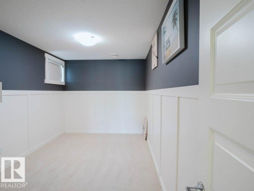 Basement: Interior room featuring light-colored carpeting, white wainscoting, and a contrasting dark wall above - 15867 11 Avenue, Edmonton, AB - Indoor Photo Showing Other Room