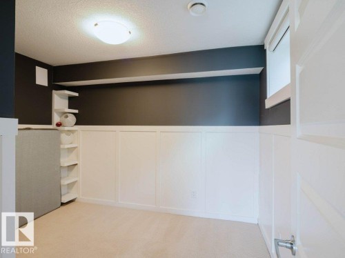 Basement: Room featuring dark accent walls, white wainscoting, and neutral carpet flooring - 15867 11 Avenue, Edmonton, AB - Indoor Photo Showing Other Room