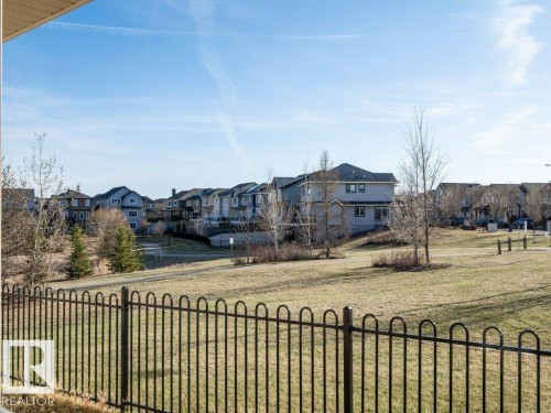 Ornamental metal fence bordering a green space with mature trees and a paved pathway - 15867 11 Avenue, Edmonton, AB - Outdoor