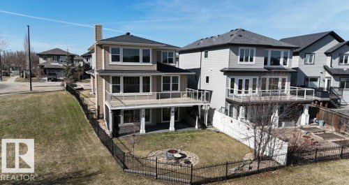 Rear exterior featuring two levels of outdoor living space, including a covered patio and an upper-level deck with glass railings - 15867 11 Avenue, Edmonton, AB - Outdoor With Deck Patio Veranda