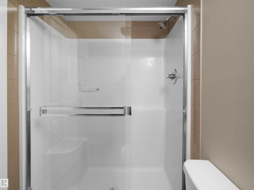 Walk-in shower with clear glass sliding doors and chrome hardware - 417 1060 Mcconachie Boulevard, Edmonton, AB - Indoor Photo Showing Bathroom
