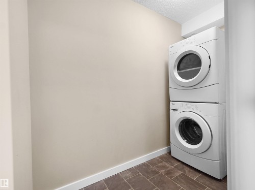 Laundry area featuring a stacked washer and dryer, tile flooring, and neutral wall tones - 417 1060 Mcconachie Boulevard, Edmonton, AB - Indoor Photo Showing Laundry Room