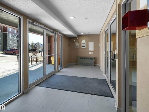 Entryway featuring multiple clear glass doors with metal frames, light-colored tile flooring, beige painted walls, and recessed lighting - 417 1060 Mcconachie Boulevard, Edmonton, AB -  Photo Showing Other Room