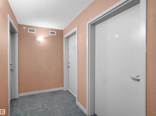 Hallway featuring textured peach-toned walls and a patterned carpet floor - 417 1060 Mcconachie Boulevard, Edmonton, AB - Indoor Photo Showing Other Room