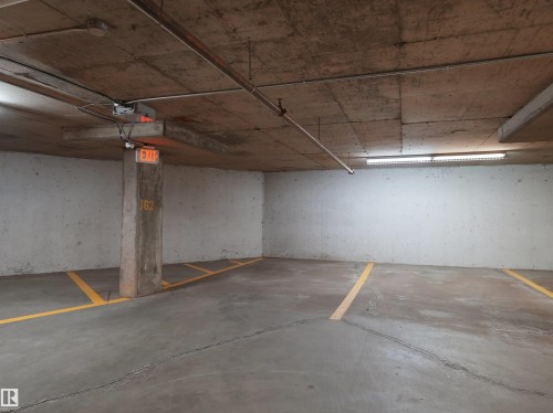 Underground parking space featuring a concrete floor with yellow painted lines, concrete walls, and an exposed concrete ceiling - 417 1060 Mcconachie Boulevard, Edmonton, AB - Indoor Photo Showing Garage