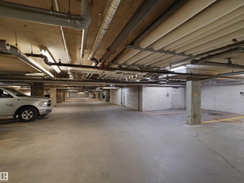 Underground parking garage featuring concrete flooring, exposed ceiling utilities, and fluorescent lighting - 417 1060 Mcconachie Boulevard, Edmonton, AB - Indoor Photo Showing Garage
