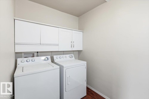 Dedicated laundry space featuring white cabinetry, wood-finish flooring, and light-toned walls - 13107 133 Street, Edmonton, AB - Indoor Photo Showing Laundry Room