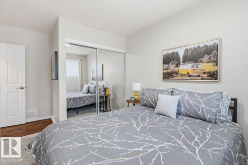 Bedroom featuring neutral wall paint, mirrored closet doors, a white paneled door, and carpeted flooring - 13107 133 Street, Edmonton, AB - Indoor Photo Showing Bedroom