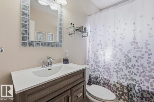 Bathroom vanity featuring a white integral sink, chrome faucet, and wood-finish cabinetry - 13107 133 Street, Edmonton, AB - Indoor Photo Showing Bathroom