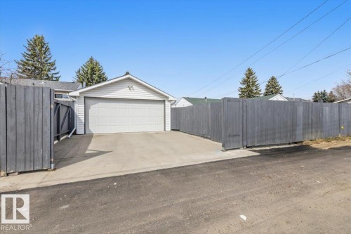 Detached garage structure featuring white horizontal siding and a large panel garage door - 13107 133 Street, Edmonton, AB - Outdoor
