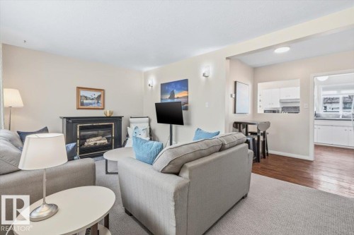 Living area featuring a fireplace with a dark mantle and hearth, wall sconce lighting, and a broad pass-through window to the kitchen - 13107 133 Street, Edmonton, AB - Indoor Photo Showing Living Room With Fireplace
