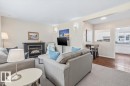 Living area featuring a fireplace with a dark mantle and hearth, wall sconce lighting, and a broad pass-through window to the kitchen - 13107 133 Street, Edmonton, AB  - Indoor Photo Showing Living Room With Fireplace 