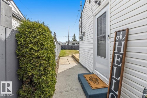 White siding exterior featuring a storm door, concrete walkway, and a privacy fence - 13107 133 Street, Edmonton, AB - Outdoor With Exterior