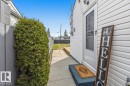White siding exterior featuring a storm door, concrete walkway, and a privacy fence - 13107 133 Street, Edmonton, AB  - Outdoor With Exterior 