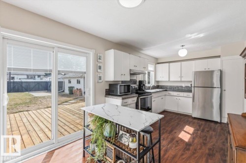 Kitchen with white cabinetry, dark countertops, and stainless steel appliances - 13107 133 Street, Edmonton, AB - Indoor Photo Showing Kitchen