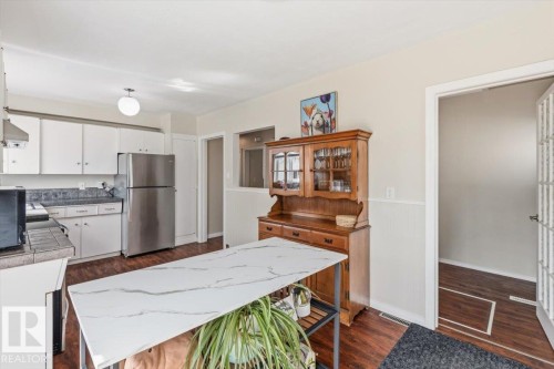 Kitchen featuring white cabinetry, stainless steel refrigerator, and wood-finish flooring - 13107 133 Street, Edmonton, AB - Indoor Photo Showing Other Room