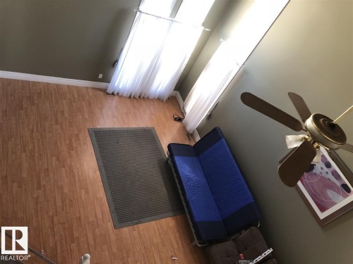 Upper-level perspective showcasing wood-finish flooring, high ceilings, multiple tall windows with white sheer curtains, and a ceiling fan with light fixture - 11507 141 Avenue, Edmonton, AB - Indoor Photo Showing Other Room