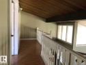 Open hallway featuring wood-finish flooring, a white spindle railing, and an angled wood-paneled ceiling - 11507 141 Avenue, Edmonton, AB  - Indoor Photo Showing Other Room 