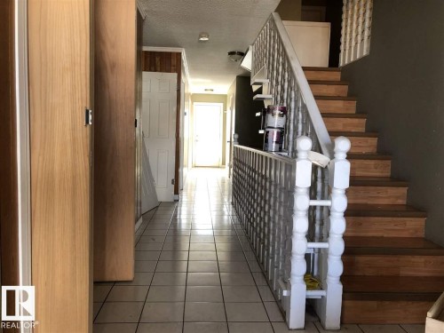 Entryway featuring a tiled floor, wood-finish staircase with white balusters, and a light-filled corridor - 11507 141 Avenue, Edmonton, AB - Indoor Photo Showing Other Room