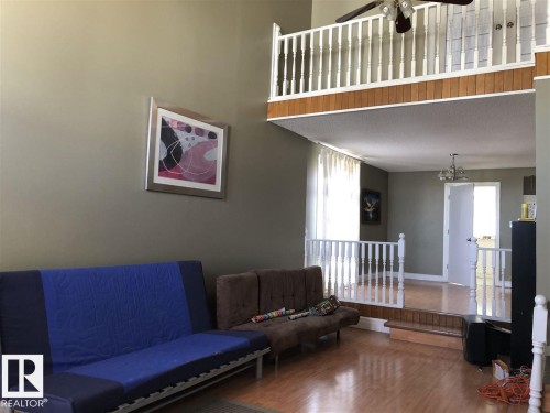 Expansive living area with vaulted ceilings, wood-finish flooring, and a second-story interior balcony with white spindle railing - 11507 141 Avenue, Edmonton, AB - Indoor
