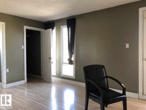 Spacious room featuring wood-finish flooring, two large windows with white trim, and a white interior door - 11507 141 Avenue, Edmonton, AB - Indoor Photo Showing Other Room
