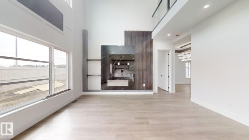 Grand living space featuring a floor-to-ceiling fireplace with dark marble-look surround, integrated shelving, and a wood-slat accent wall - 1707 18 Street Nw, Edmonton, AB - Indoor Photo Showing Other Room