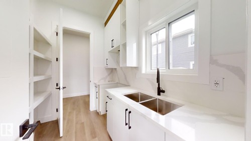 Kitchen sink area with a double basin stainless steel sink, matte black faucet, and white countertops - 1707 18 Street Nw, Edmonton, AB - Indoor Photo Showing Kitchen With Double Sink