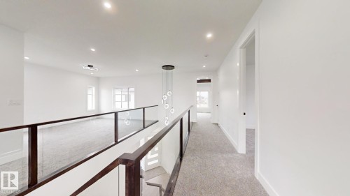 Open concept upper level featuring a glass railing, recessed lighting, a contemporary chandelier, and light-toned carpeting - 1707 18 Street Nw, Edmonton, AB - Indoor Photo Showing Other Room
