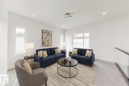Open concept room featuring recessed lighting, a modern ceiling fixture, multiple windows with white trim, and a glass railing - 1707 18 Street Nw, Edmonton, AB - Indoor Photo Showing Living Room