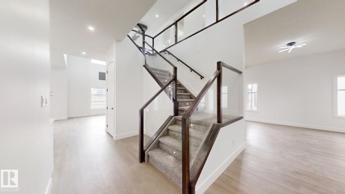 Contemporary staircase featuring glass panels, dark wood-finish handrails, and carpeted treads - 1707 18 Street Nw, Edmonton, AB - Indoor Photo Showing Other Room