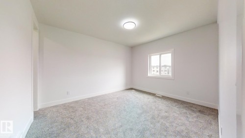 Room with light gray carpet flooring and white walls, featuring a single window with white trim and a ceiling-mounted light fixture - 1707 18 Street Nw, Edmonton, AB - Indoor Photo Showing Other Room